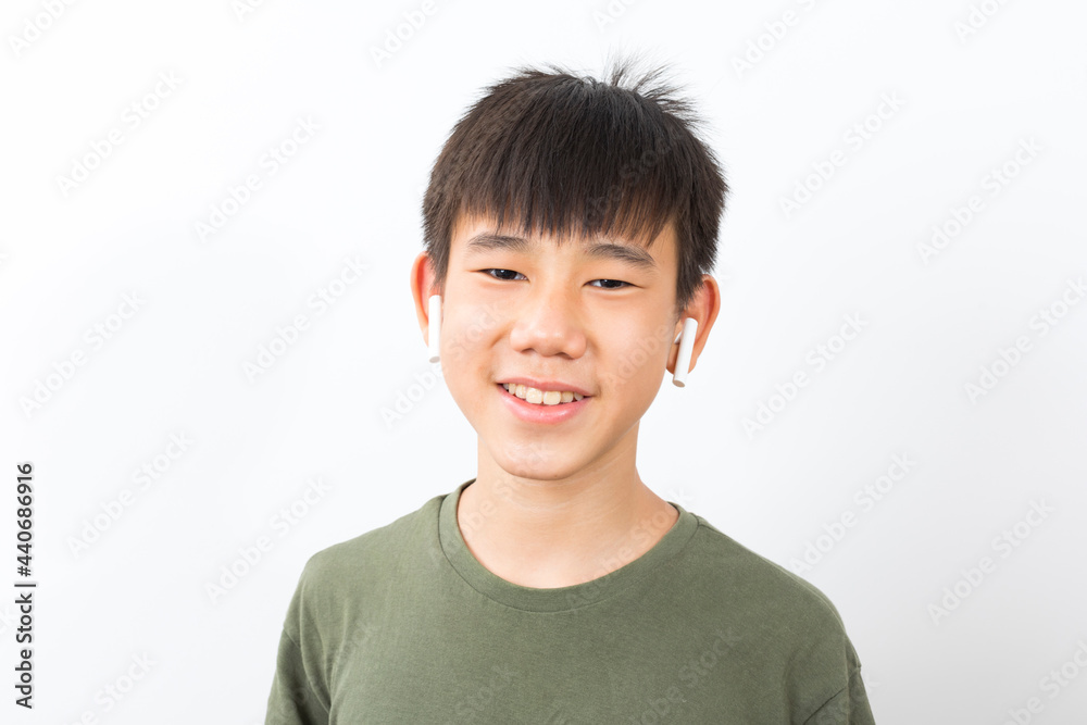 joyful Asian boy 10-12y wearing earpods smiling on white background. joyful Asian boy 10-12y wearing earpods smiling on white background.