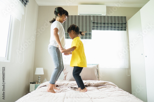 Two little girls jumping on bed when playing together
