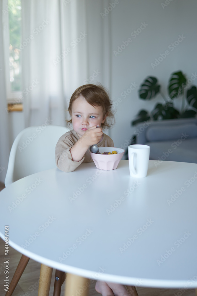 small child girl in the morning breakfast in the house at a white round table small child girl in the morning breakfast in the house at a white round table