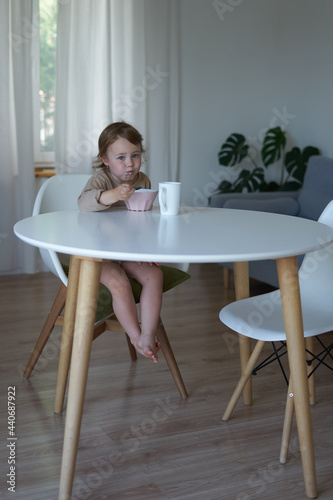 small child girl in the morning breakfast in the house at a white round table