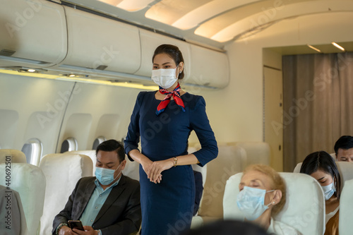 Air hostess wearing protective mask to Protect Against Covid-19 checking the orderliness of the plane passengers before plane taking off,Air travel during the coronavirus pandemic.