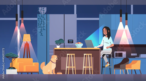 overworked businesswoman freelancer looking at laptop screen woman with dog working in dark night kitchen