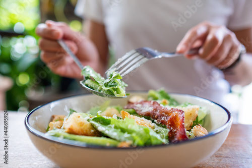 Closeup image of a woman eating a Caesar salad