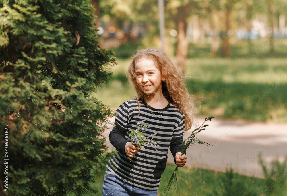 Little girl cheerfully runs on the grass in the park in the summer. Little girl cheerfully runs on the grass in the park in the summer.