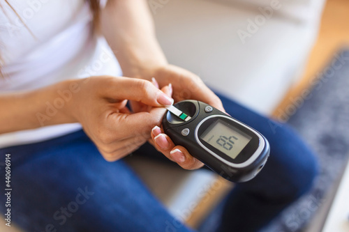 Woman with glucometer checking blood sugar level at home. Diabetes, health care concept