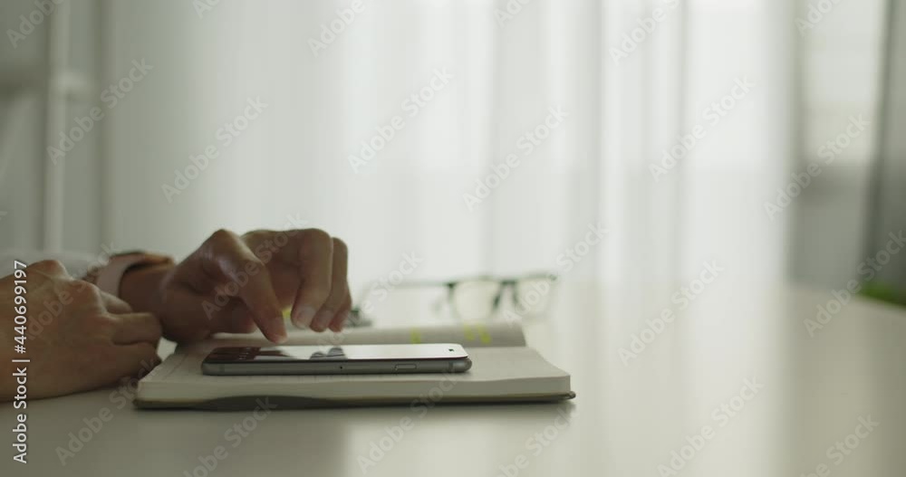 Businessman sitting on a chair in an office room using a smartphone, scrolling through social media, or watching online content, communications concept. Close Up Shot. Businessman sitting on a chair in an office room using a smartphone, scrolling through social media, or watching online content, communications concept. Close Up Shot.