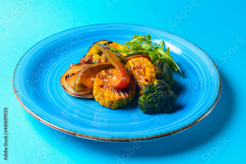 Delicious grilled vegetables served on a blue plate over blue background. BBQ Grill concept. photo