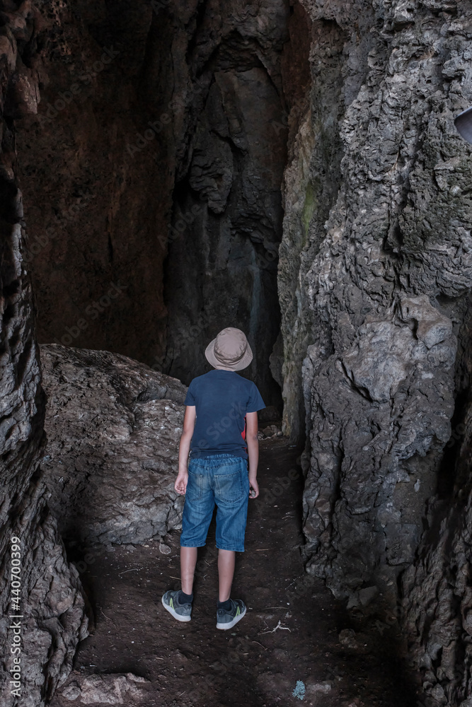 A boy standing inside a through grotto located in the rock, National botanical reserve New World, Crimea.