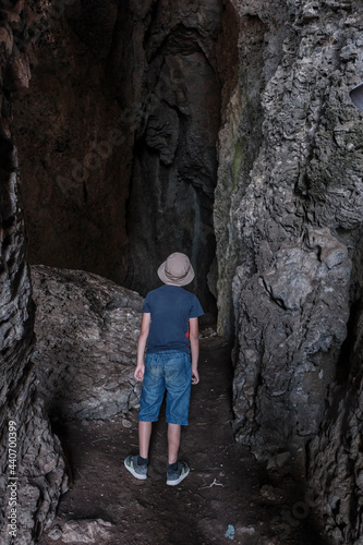 A boy standing inside a through grotto located in the rock, National botanical reserve New World, Crimea.