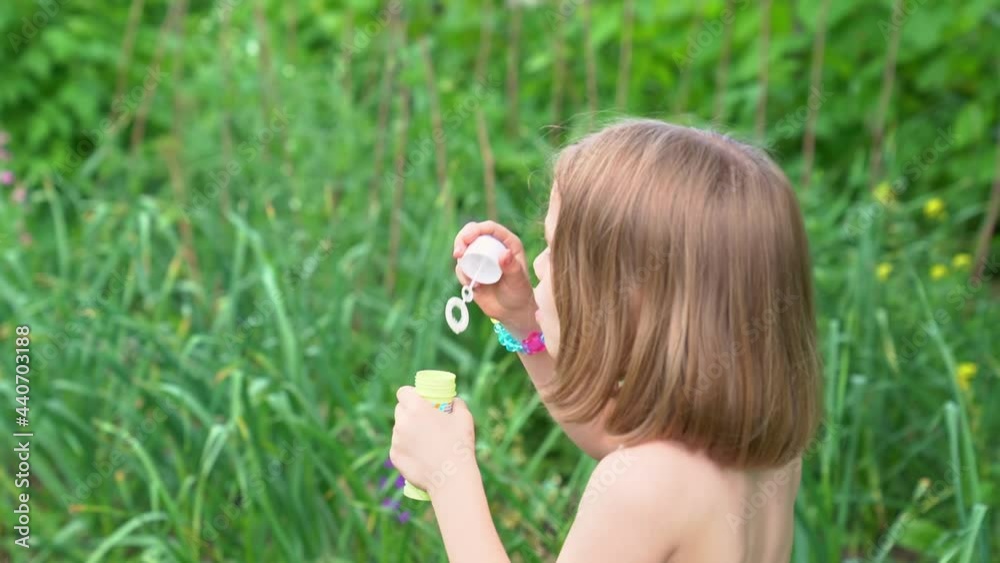 A girl inflates soap bubbles in a meadow. happy childhood and fun for children A girl inflates soap bubbles in a meadow. happy childhood and fun for children