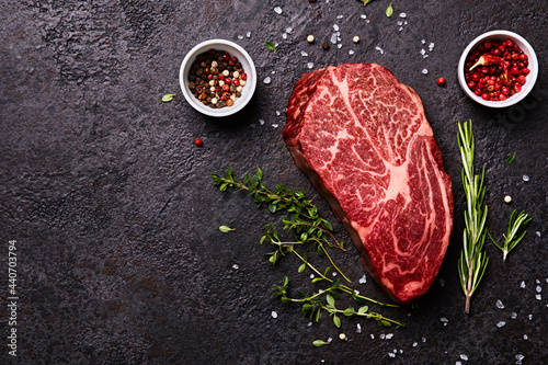 Stampa su tela Fresh raw marbled beef rib eye steak and spices on black stone background, copy