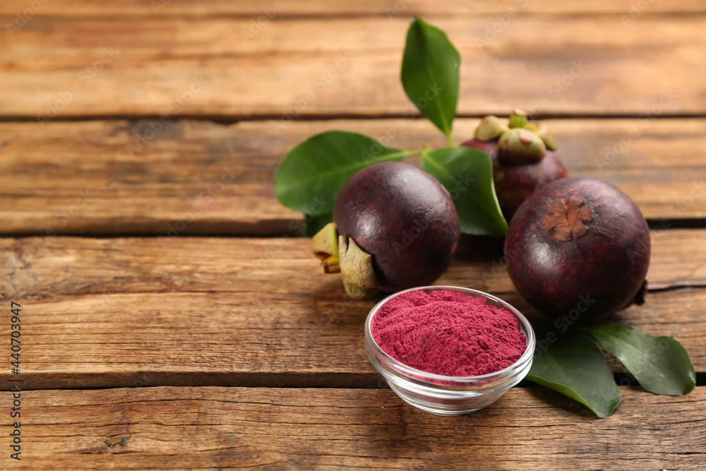 Purple mangosteen powder and fruits on wooden table. Space for text Purple mangosteen powder and fruits on wooden table. Space for text