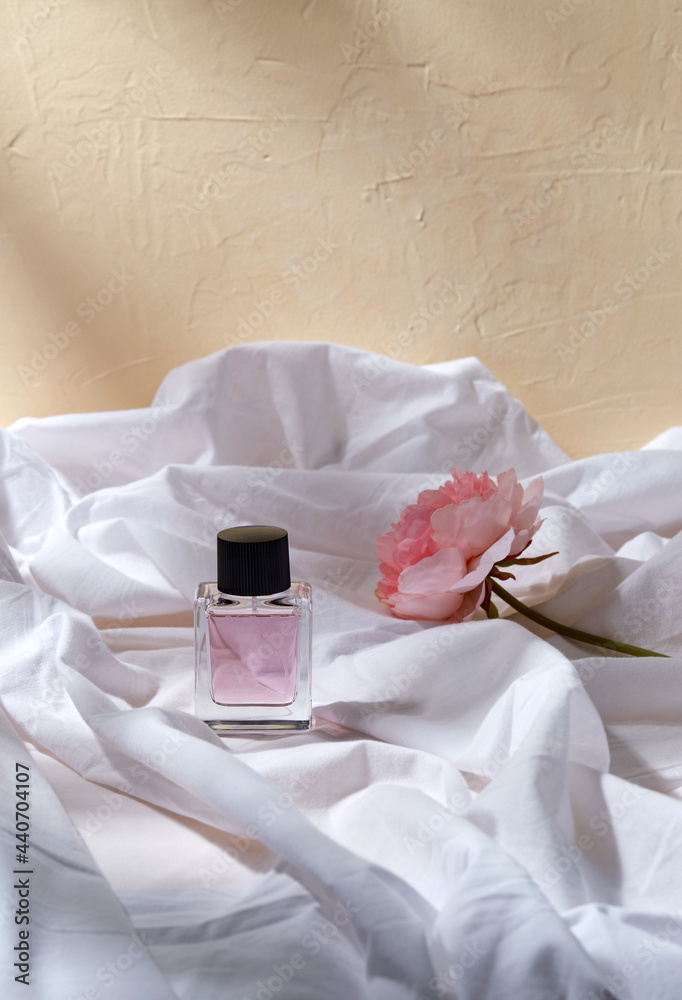 beauty, perfumery and object concept - bottle of perfume and flower on white sheet with folds beauty, perfumery and object concept - bottle of perfume and flower on white sheet with folds