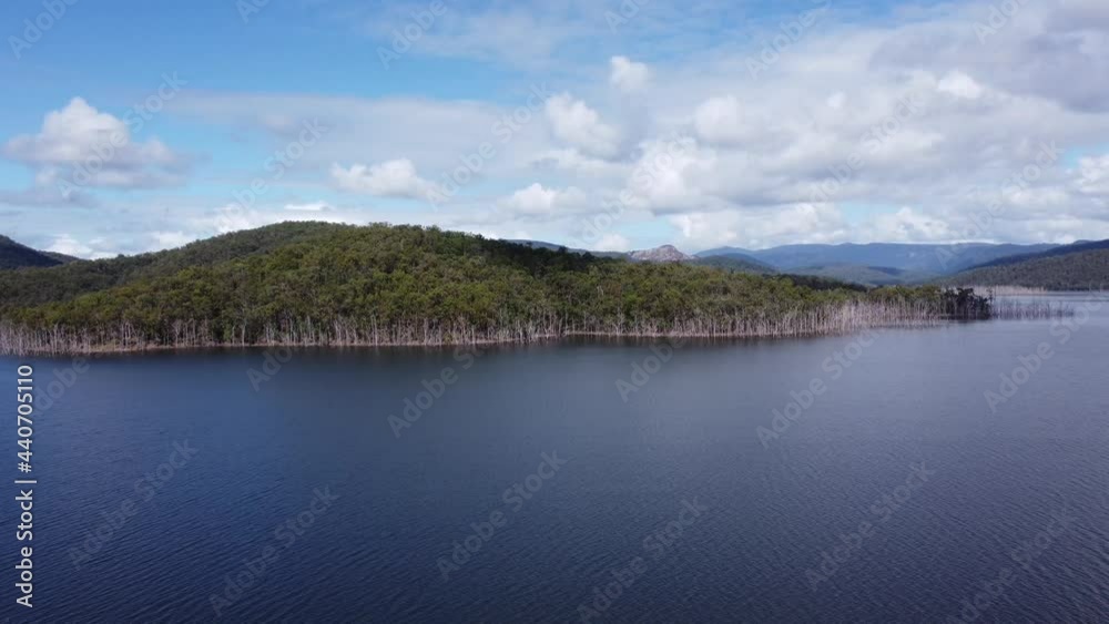 Slow flight over water towards a green hill Slow flight over water towards a green hill