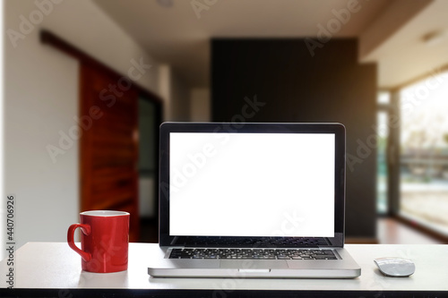 Front view of cup and laptop, smartphone, and tablet on table in office