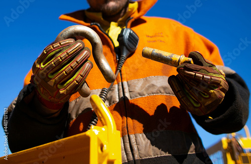 Safety workplace close up image of trained competent rigger high risk worker wearing safety heavy duty glove inspecting D- shape shackle pin prior inserting into crane lifting lug cate during lifting photo