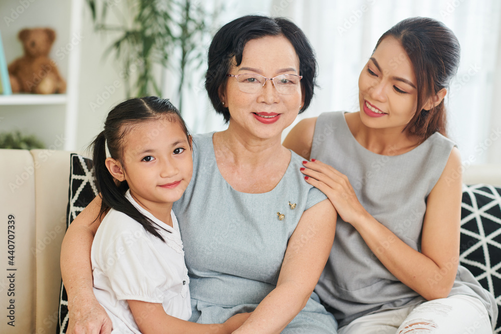 Happy smiling senior woman enjoying spending time with her adult daughter and preteen granddaughter at home on weekend Happy smiling senior woman enjoying spending time with her adult daughter and preteen granddaughter at home on weekend