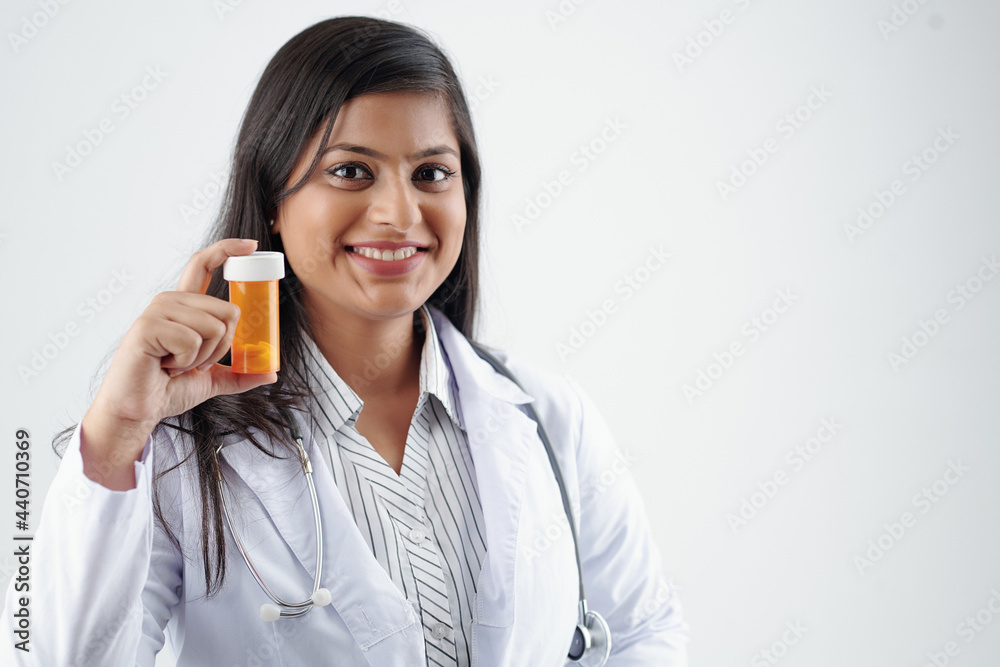 Portrait of cheerful physician showing plastic container with painkillers or vitamins Portrait of cheerful physician showing plastic container with painkillers or vitamins