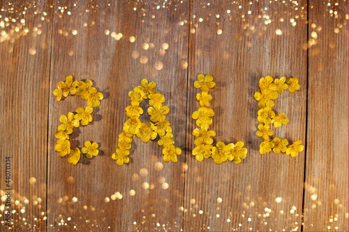  beautiful inscription sale, laid out of buttercup flowers on a wooden background