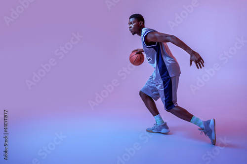 Basketball player practicing with ball in studio