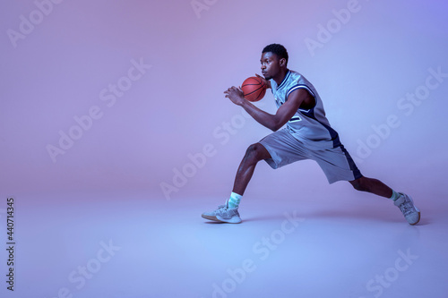 Basketball player practicing with ball in studio