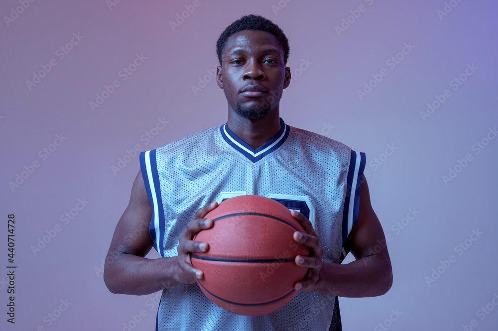Confident basketball player poses with ball Confident basketball player poses with ball
