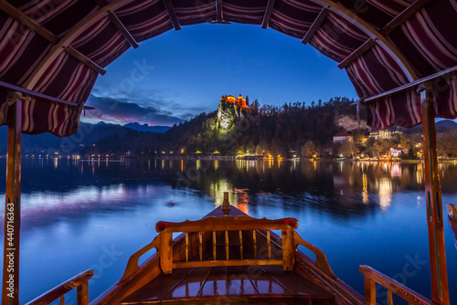 Tourist boat frames the iconic Bled Castle in the evening