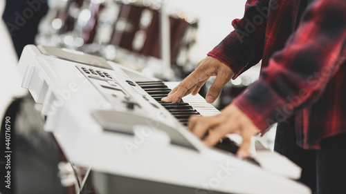 Close-up shot of male musician hands playing the electric keyboard. Selective focus on the hands with a drum in the background. Professional pianist practicing and rehearsing prepare for competition