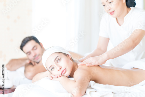 Young woman and man lying on the spa bed. Young beautiful white woman lying on a massage table and is being massaged. in Thailand resort.