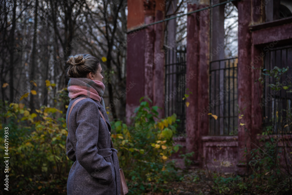 A young woman looks at the ruins of an old building - an abandoned family home. The concept of a belated return to basics A young woman looks at the ruins of an old building - an abandoned family home. The concept of a belated return to basics