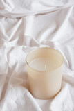 aroma candle on white crumpled cotton fabric