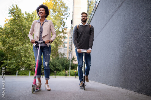 Young couple on vacation having fun driving electric scooter through the city.