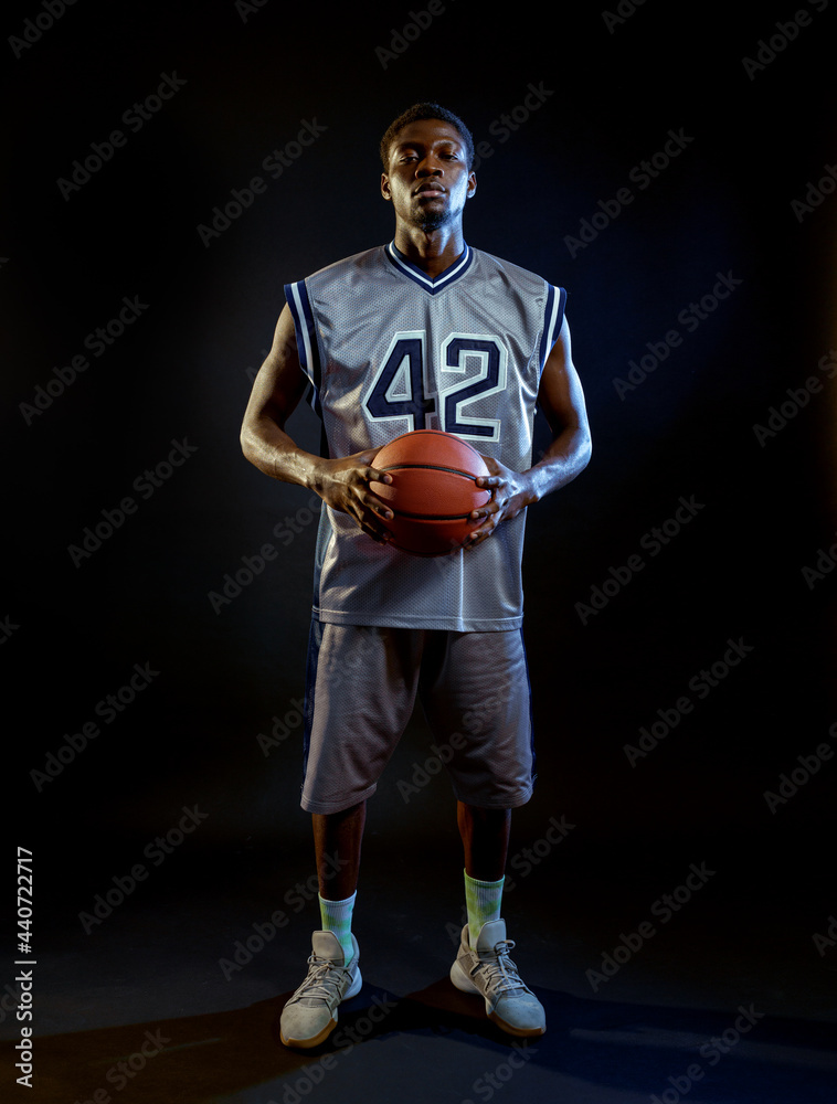 Focused basketball player holds ball in studio Focused basketball player holds ball in studio
