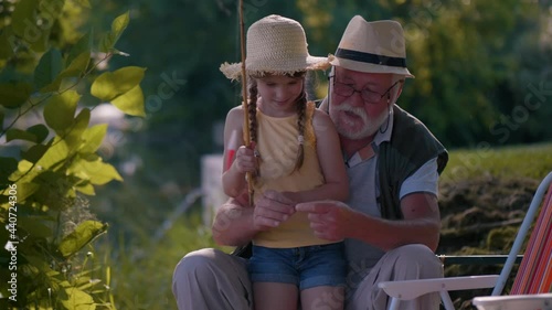 Grandpa helps his granddaughter put the bait on the hook photo