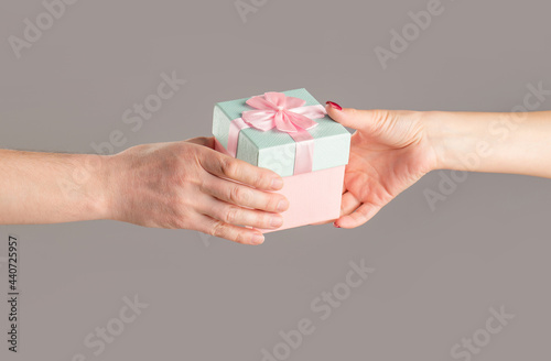 Male and female hands holding pink gift box. Girl gives a gift to man. Woman hands holding gift. Gift box in hand, surprise and holiday concept. Man hands holding valentines day gift