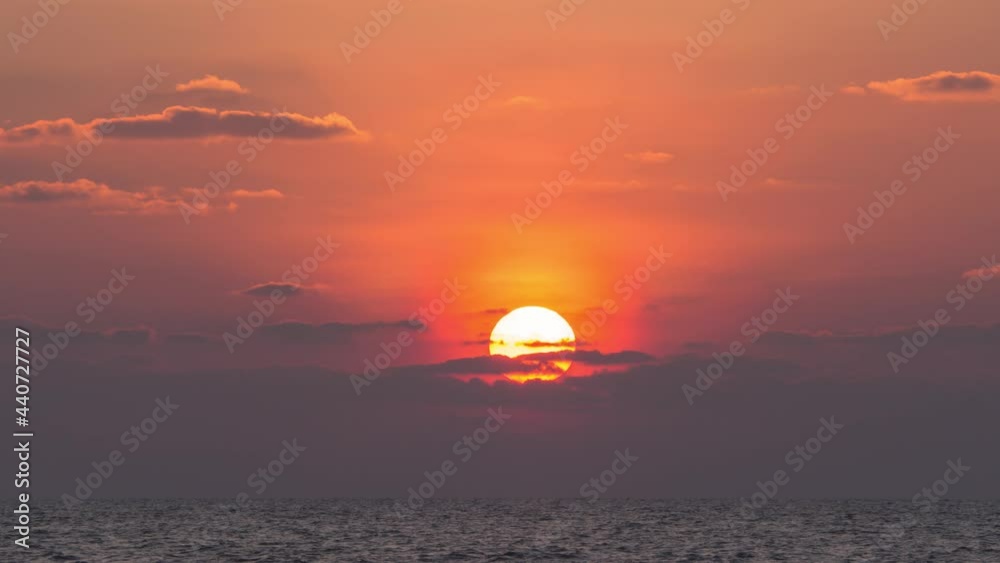Drone fly towards sunset at the horizon. Orange colorful sky at the ocean with beautiful huge sun movie through dramatic gray clouds. Sunlight reflect on water surface. Nature Timelapse 4k Backgroud