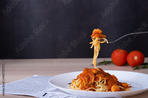 spaghetti tomato sauce on white plate with fork scoop up spaghetti shrimp on wooden table, Italian foodmenu concept with copy space for text.  photo