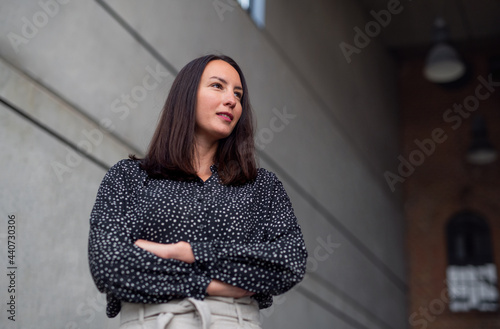 Low-angle view portrait of mid adult businesswoman standing indoors, arms crossed.