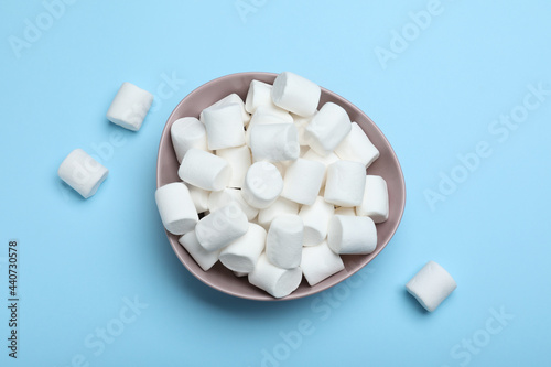 Delicious puffy marshmallows on light blue background, flat lay