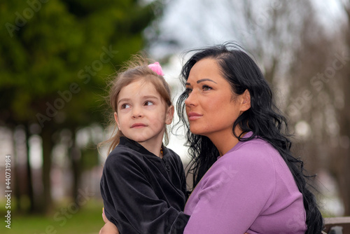 Cute 5 years old girl and her mom sit on a park bench in summer.Family and lifestyle concept.Closeup.