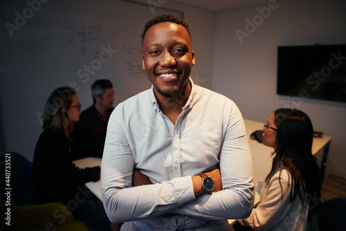 Portrait of smiling african business manager posing in front of his colleague working at background