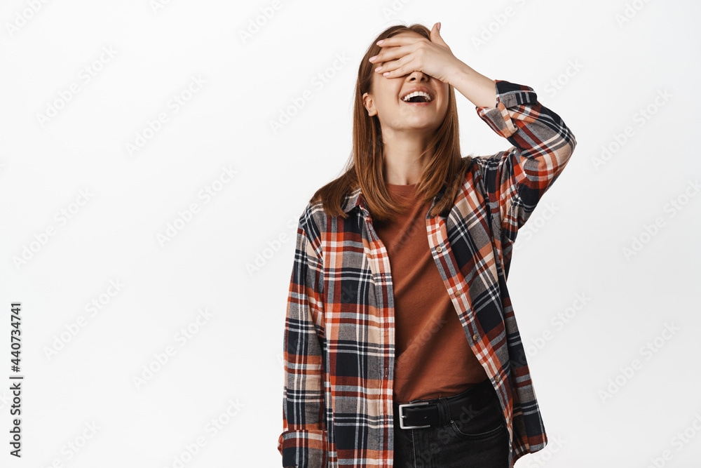 Image of happy blond girl waiting for surprise, close eyes, cover with hand and smiling excited, playing hide n seek, standing against white background Image of happy blond girl waiting for surprise, close eyes, cover with hand and smiling excited, playing hide n seek, standing against white background
