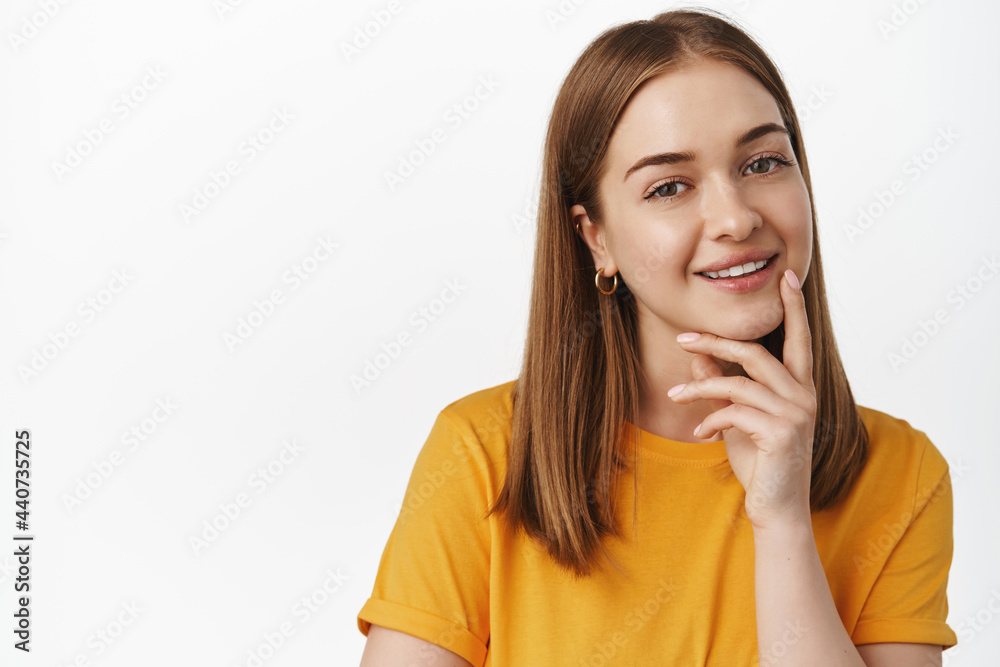 Close up portrait of smiling blond woman look intrigued, smiling thoughtful, interesting suggestion, standing pleased in yellow t-shirt against white background Close up portrait of smiling blond woman look intrigued, smiling thoughtful, interesting suggestion, standing pleased in yellow t-shirt against white background