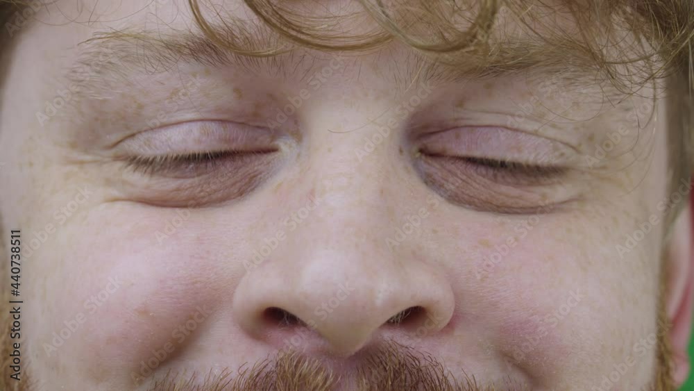 Mens gray open eyes. Redhead male with curly hair and freckles looks directly into the camera and smiles. Close up macro portrait. Slow motion ready 59.97fps.