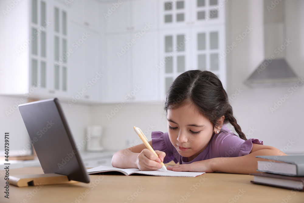 Little girl doing homework with modern tablet at home Little girl doing homework with modern tablet at home