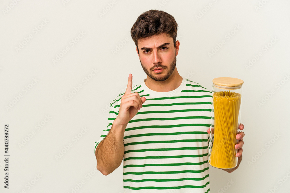 Young caucasian woman holding pasta jar isolated on white background showing number one with finger. Young caucasian woman holding pasta jar isolated on white background showing number one with finger.