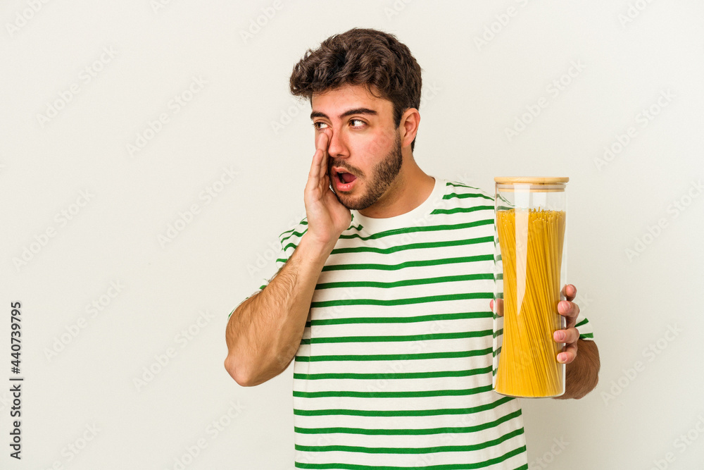 Young caucasian woman holding pasta jar isolated on white background is saying a secret hot braking news and looking aside Young caucasian woman holding pasta jar isolated on white background is saying a secret hot braking news and looking aside