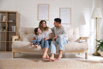 Happy family with little daughter sitting on sofa in living room
