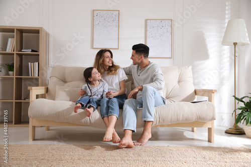 Happy family with little daughter sitting on sofa in living room