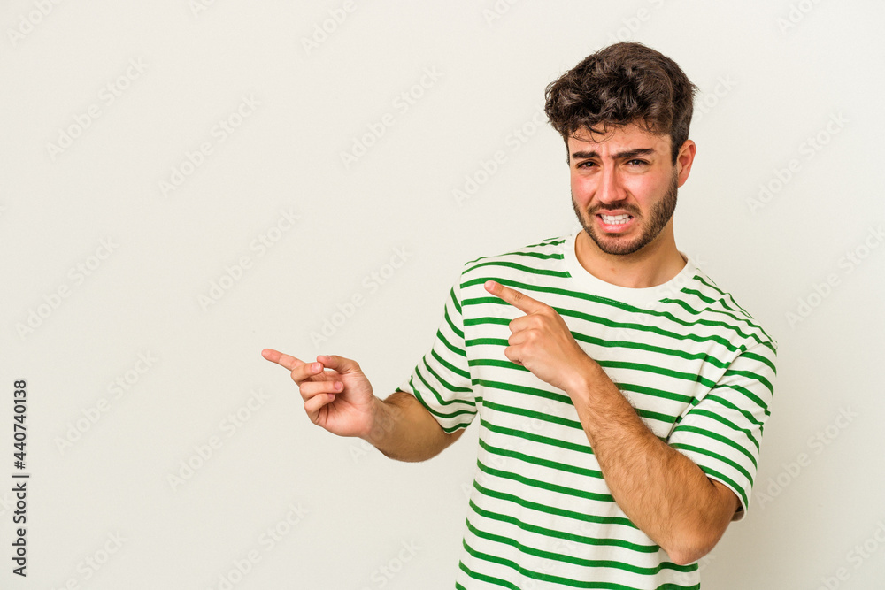 Young caucasian man isolated on white background shocked pointing with index fingers to a copy space. Young caucasian man isolated on white background shocked pointing with index fingers to a copy space.